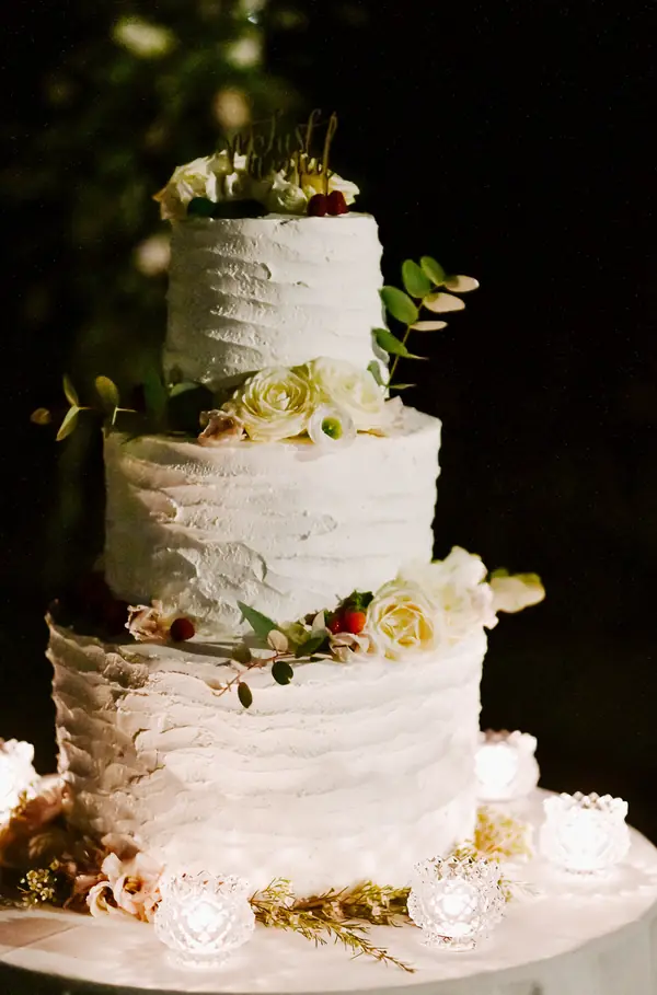 La torta nuziale a tre piani decorata con eucalipto e rose bianche