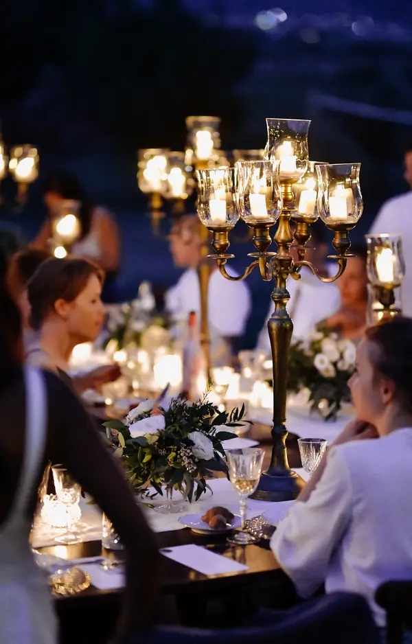 La cena all'aperto, con gli ospiti a tavola e i candelabri accesi
