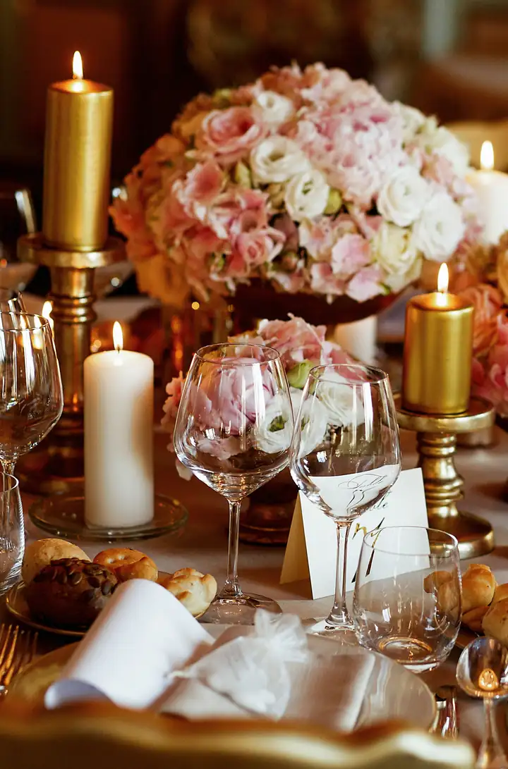 Una tavola del salone con candele, rose rosa e calici